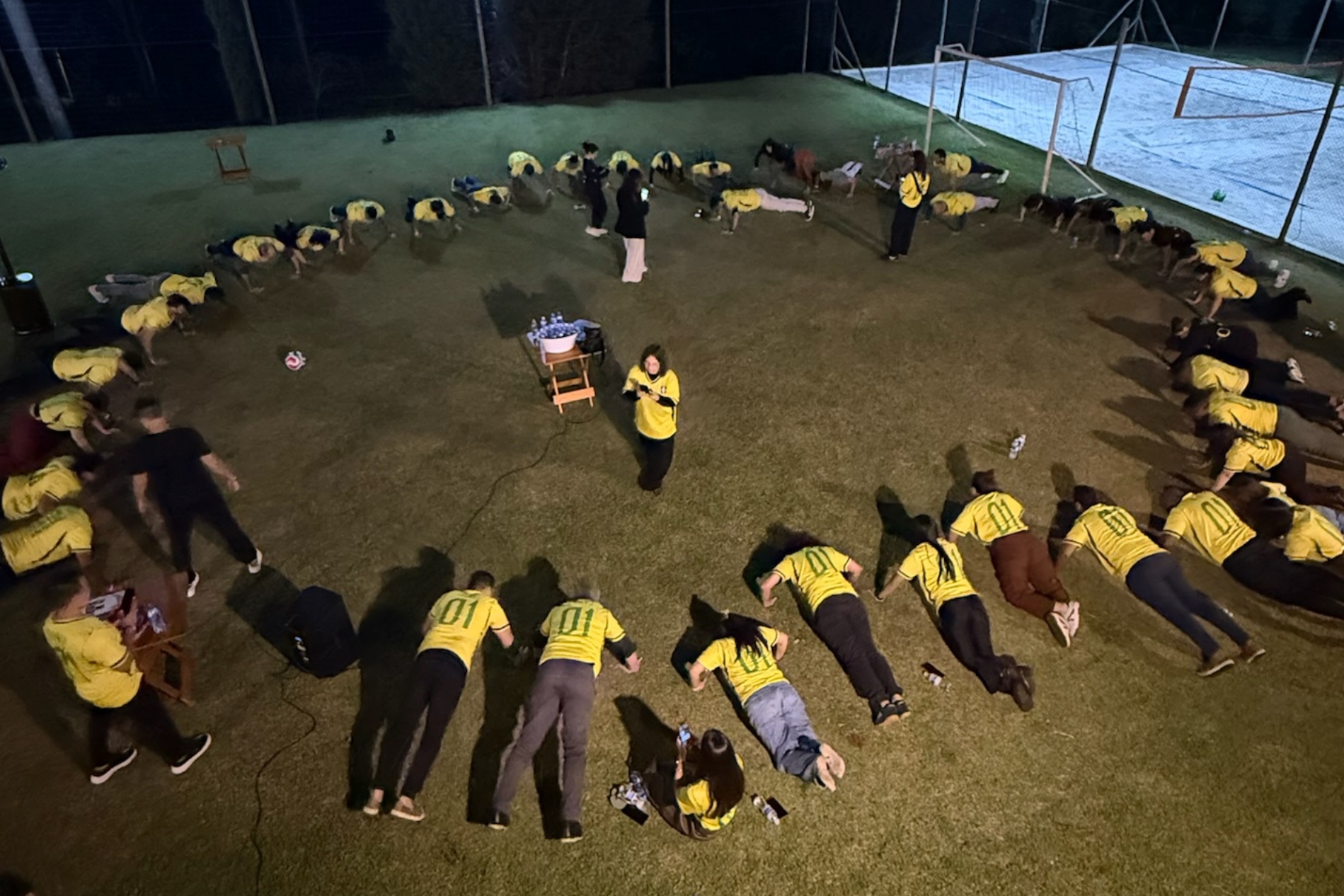 Membros do Norte Club fazendo prancha no campo de futebol, vestidos com a camisa amarela do Brasil
