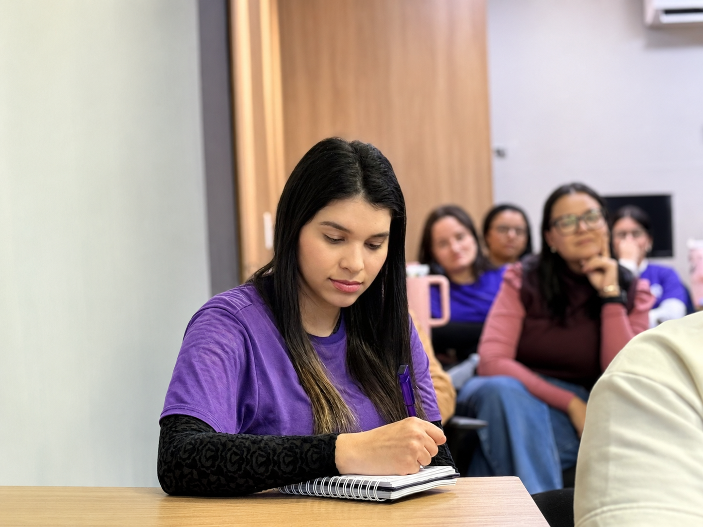 Empreendedora anotando em caderno durante treinamento da Norte sobre reforma tributária